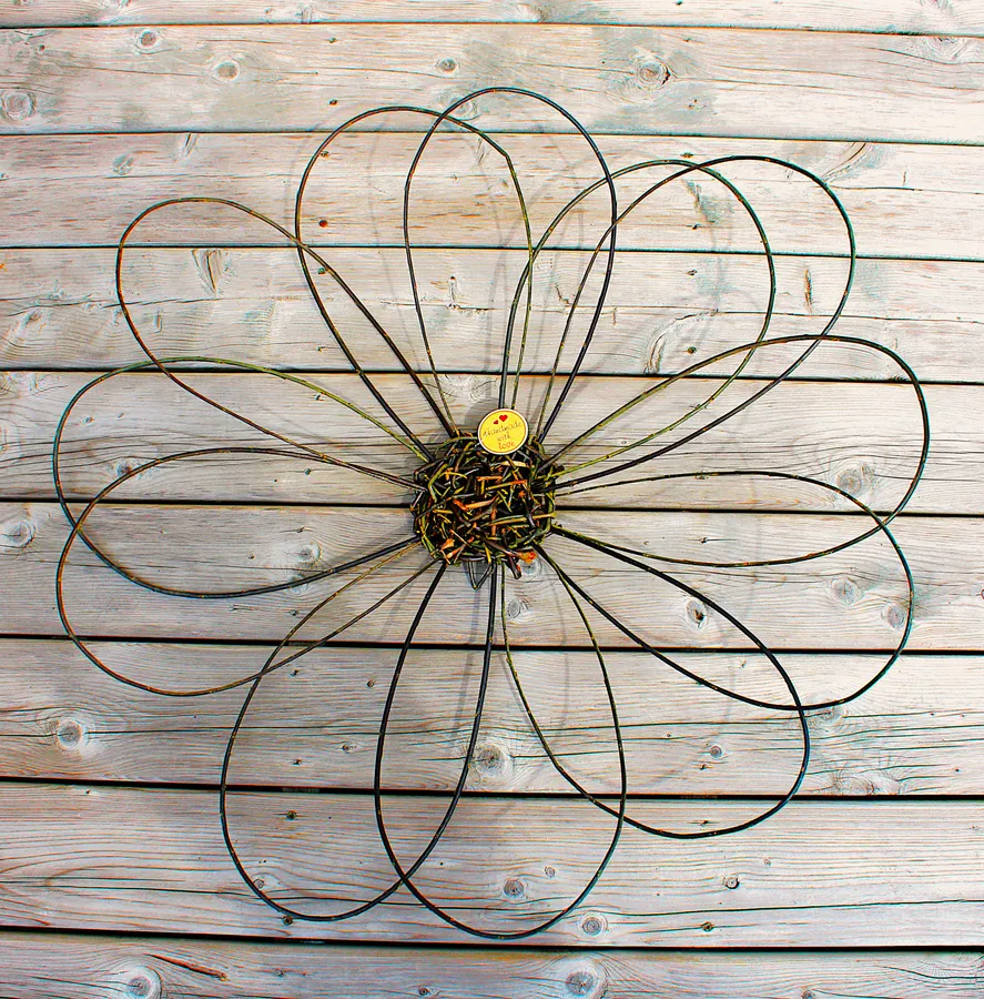 A many-petalled willow flower with a woven heart, on weathered barnboard